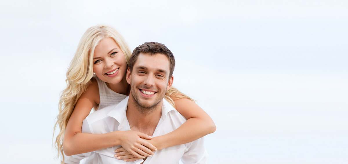 women holding man while both smile with nice teeth