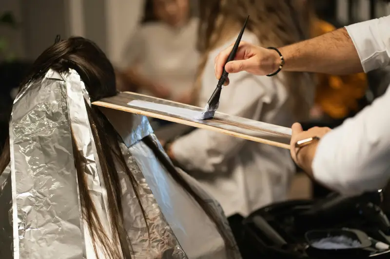 Hair stylist applying hair color using a brush 