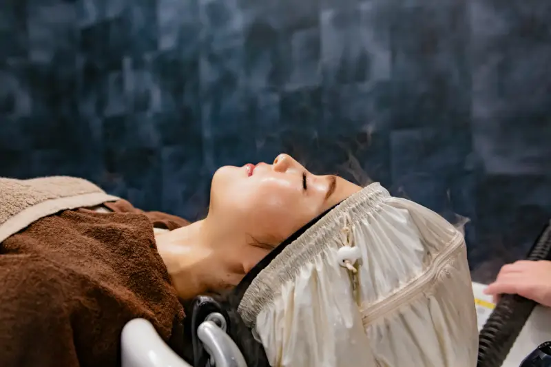 Photo of a woman having her hair covered and steamed