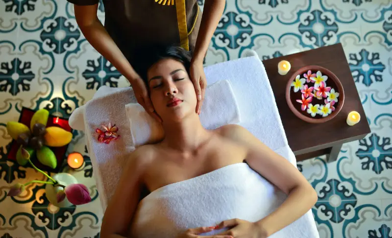 Picture of a woman laying on a massage table and having a head massage