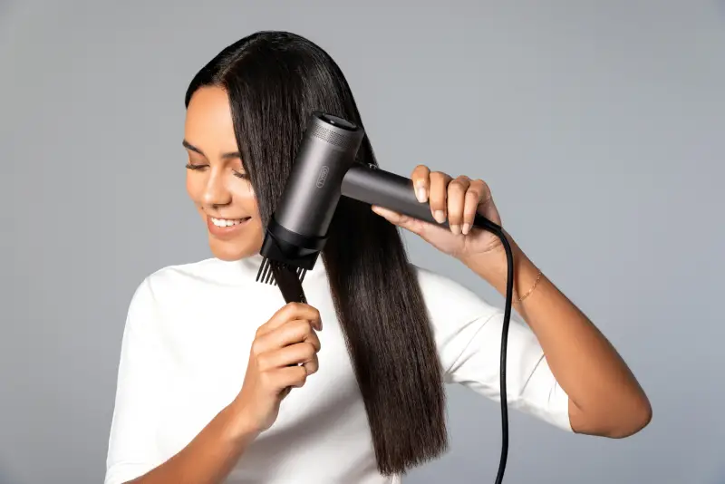 A women with dark hair blow drying her hair