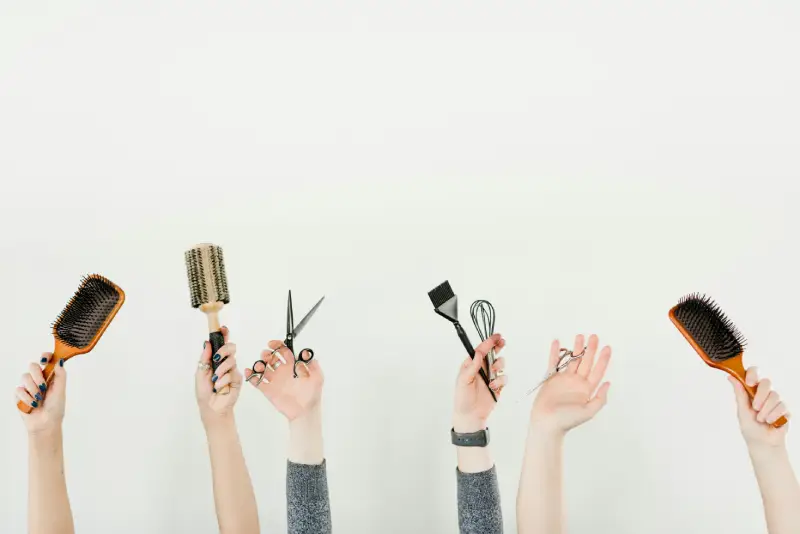 people holding up hair brushes and scissors 