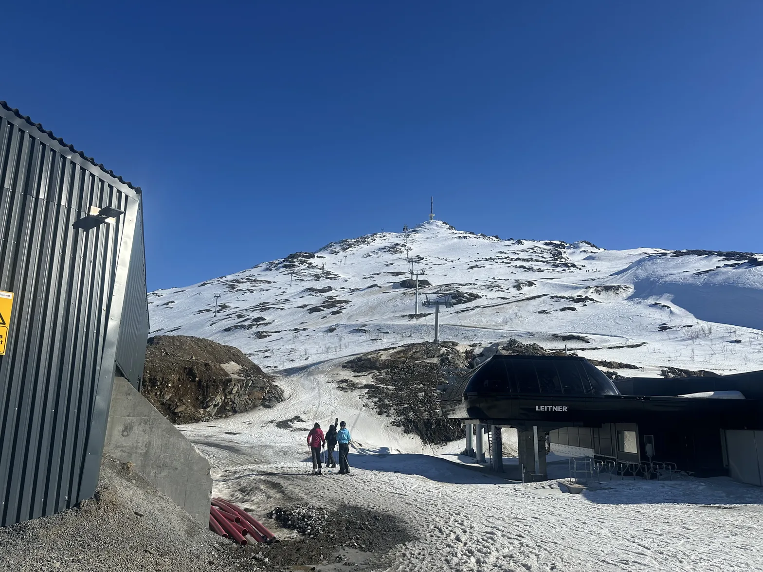 Bunnstasjonen i Narvikfjellet med gondolbanen opp fjellsiden, snø og blå himmel