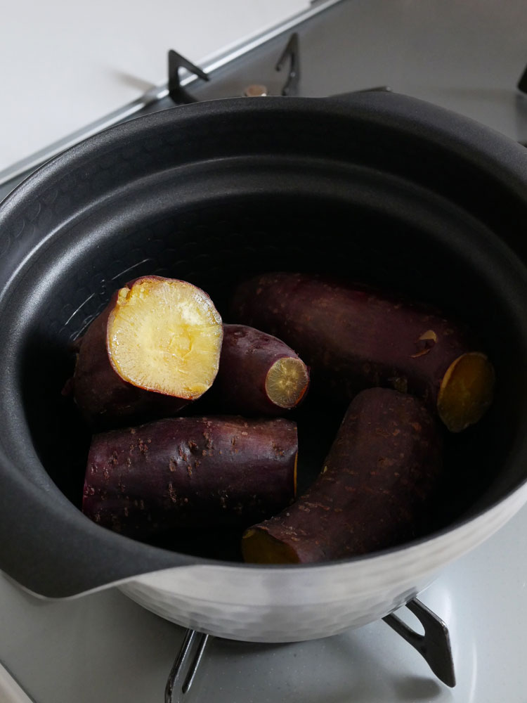 HARIO「雪平」ガラスフタ付きIH対応ご飯釜がキッチンで新鮮な野菜や調理器具とともに配置されている様子