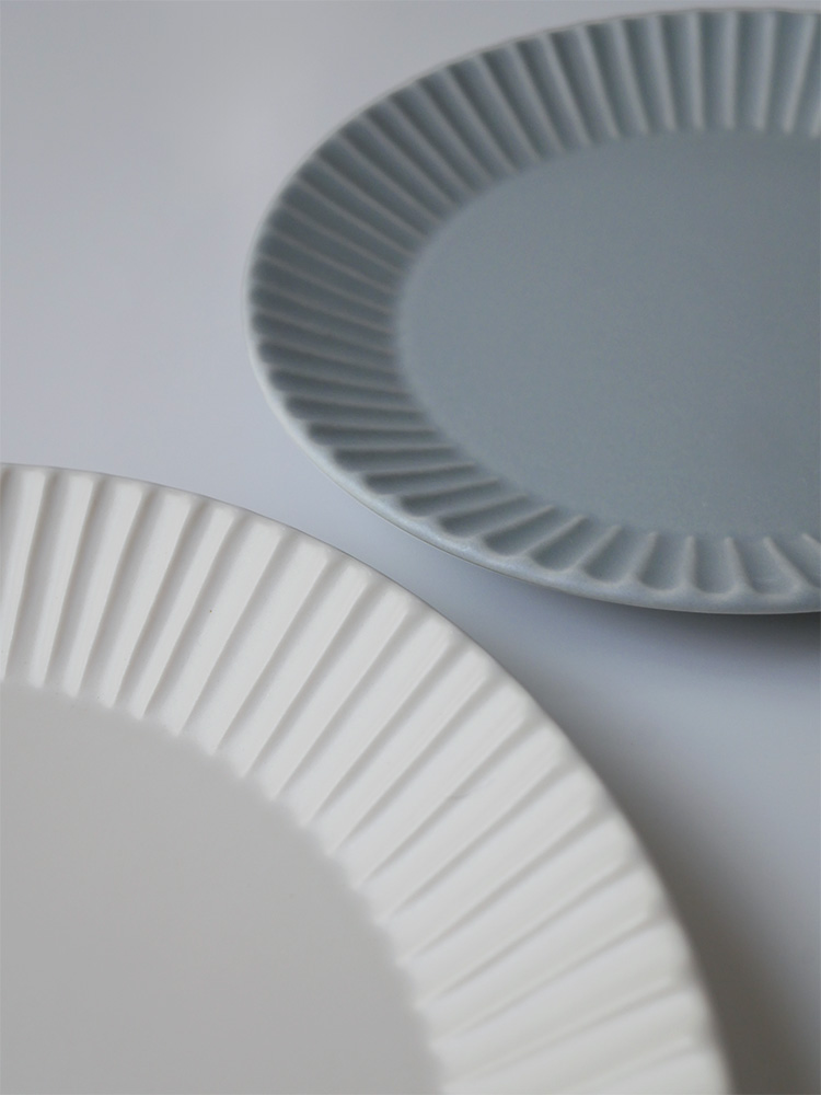 白い磁器製【SAKUZAN】Stripe 丸皿（M）がテーブルに美しく配置されている様子