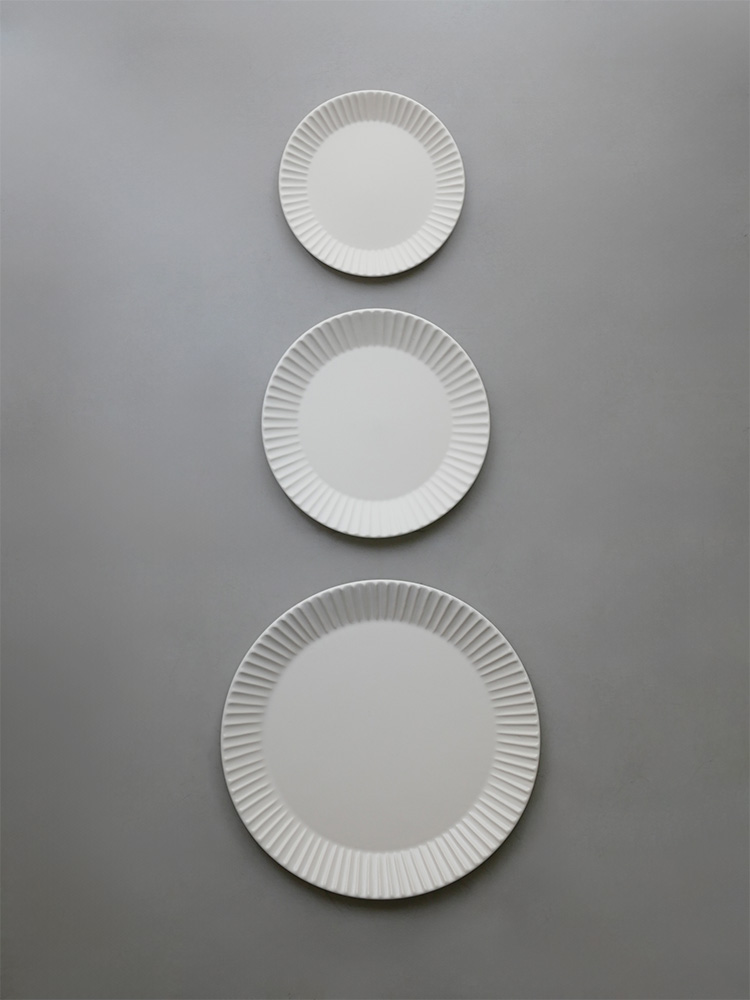 SAKUZANのStripeシリーズ白色磁器製丸皿がテーブルに美しく配置された静物写真