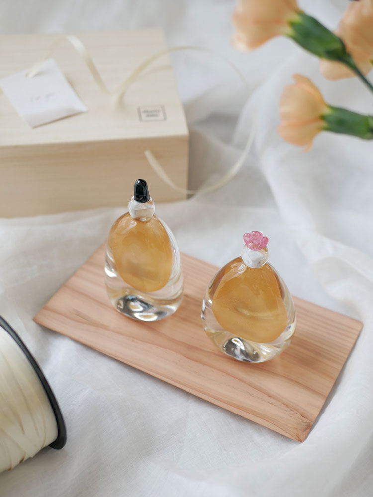 硝子屋 PRATO PINOのガラス製お雛様が木箱と飾り台とともに展示されている静物写真