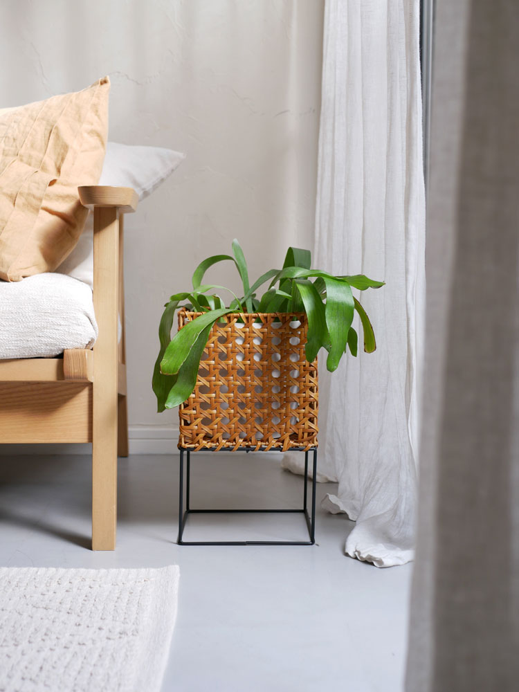 クレエのUTILE Octaポットスタンドに鉢植えが置かれ、自然素材や籠、クッション、ウィッカー製のアクセサリーと共に飾られたインテリア