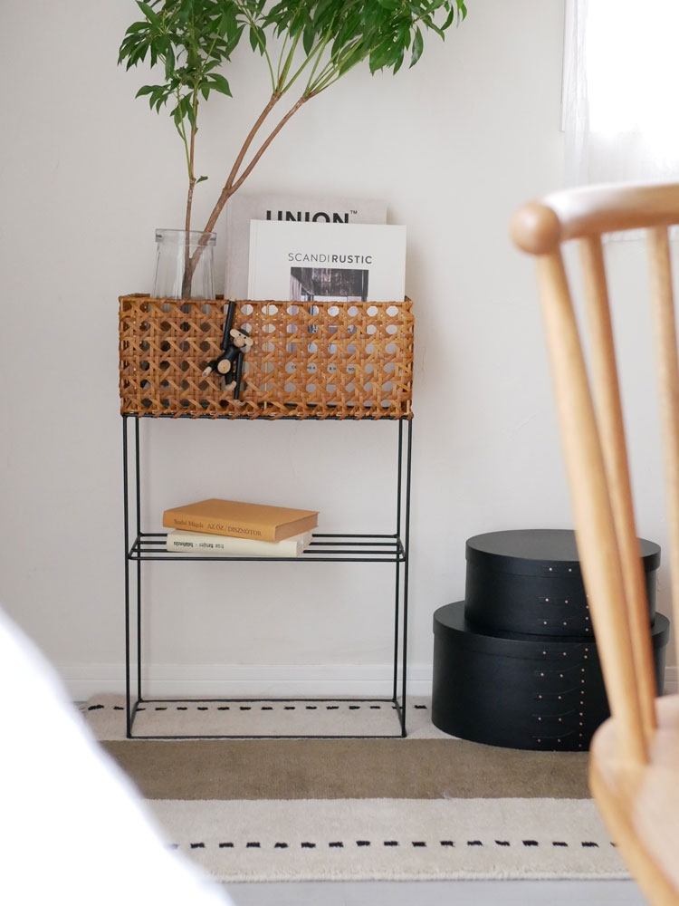 ウィッカーと木製のポットスタンドに花鉢が配置され、メッシュ製の収納バスケットが添えられたナチュラルな家具の画像