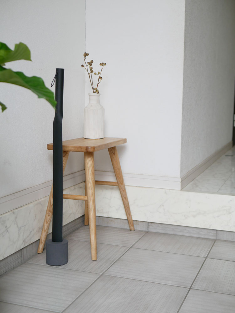 ブランドMOHEIMのSHOEHORNが木材と大理石の床、台座、観葉植物と共に配置された展示画像