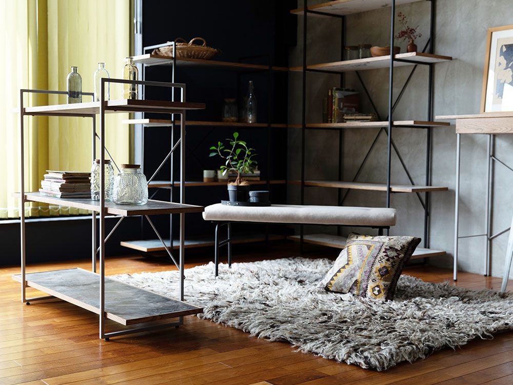 アデペシュのサムノルド クッションベンチが木製のフロアと本棚、観葉植物と共にリビングルームに配置されている様子