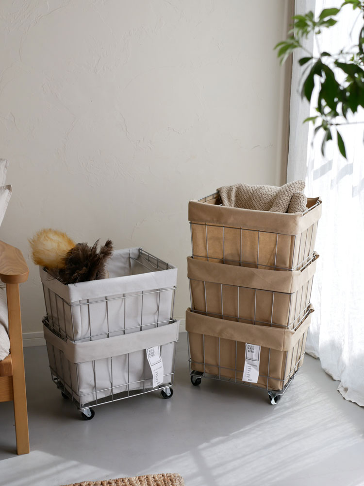 グレーのキャスター付きスタッキングバスケット【BRID/ブリッド】、ナチュラル素材でリビング用に設置された収納家具