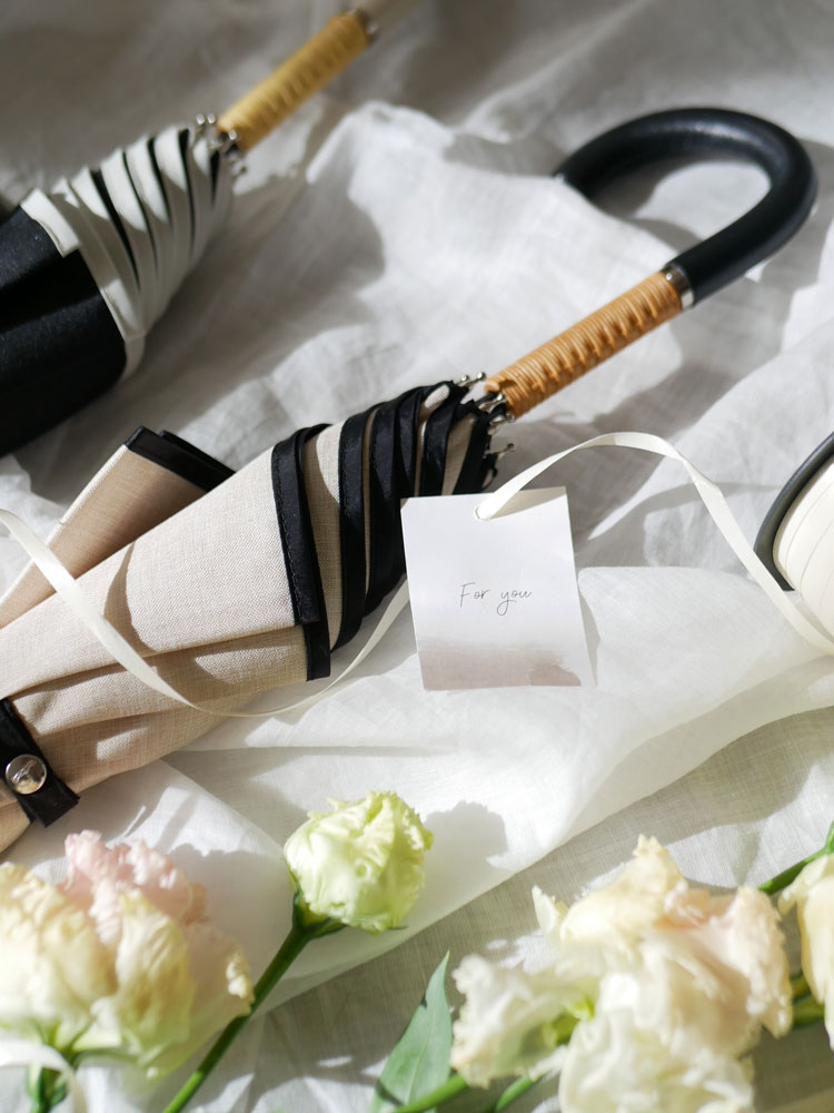 ビコーズのプレーンパイピング傘。ポリエステル100％の防水生地とラタン＋レザーのハンドルを備えた晴雨兼用タイプ。