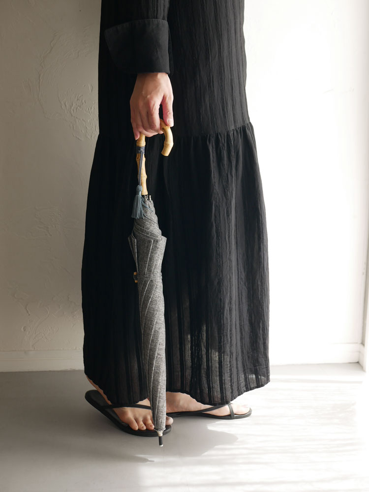 ビコーズのプレーンカラー長傘と収納バッグ。ウール製ストラップとロープを使用したナチュラルなデザインで、ポリエステルのウーブンファブリックが特徴の防水傘です。