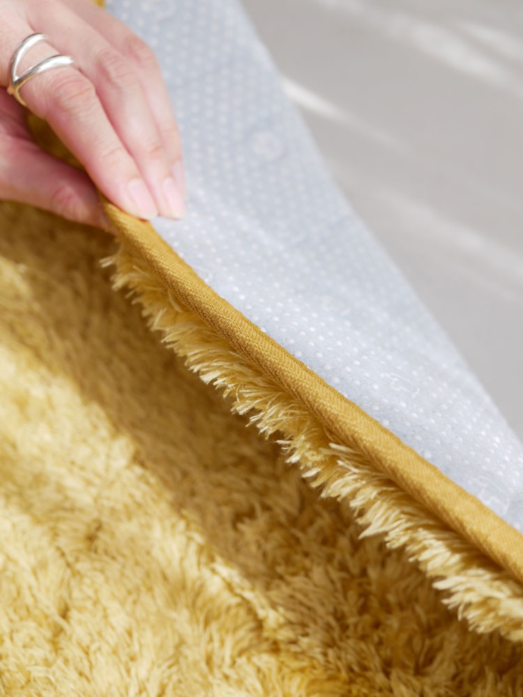 黄色の130cm直径円形ラグが木製の床に敷かれている様子