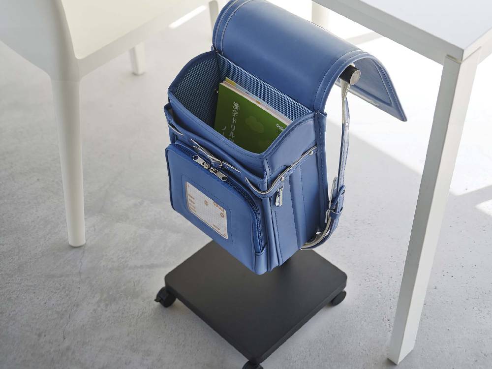 スマートランドセル収納ワゴンに複数のランドセルが整然と並べられており、スチール製のキャスターとポリプロピレン製キャップが特徴的な様子。