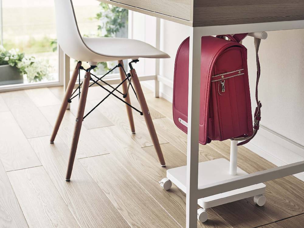 グレーのスチール製スマートランドセル収納ワゴンが木製フロア上に置かれ、近くにデスクと椅子が配置された室内の様子。