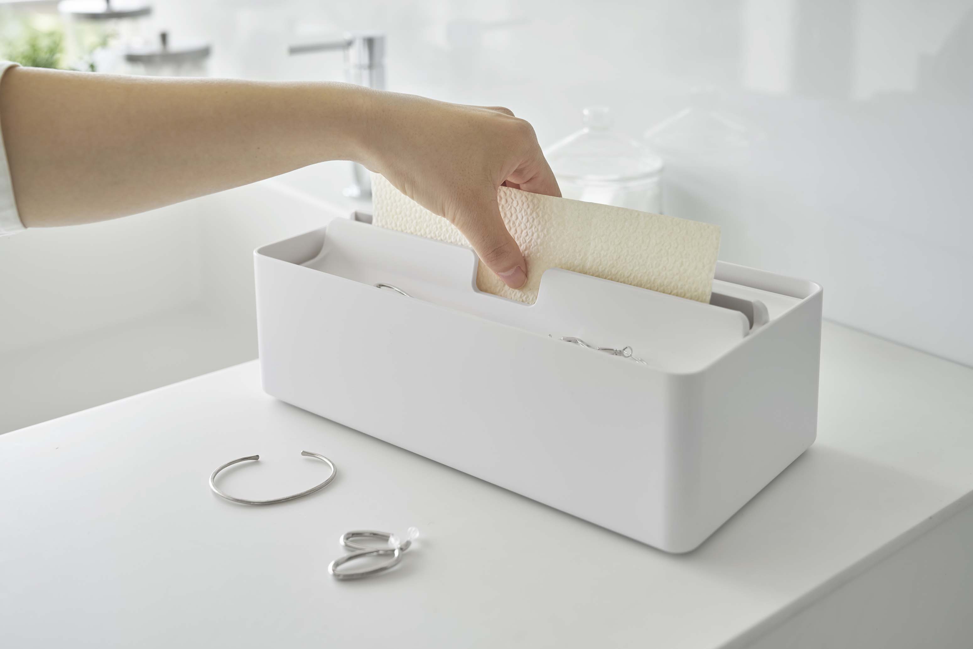 銀色のトレー蓋付きペーパータオルケース。ABS樹脂製で一般的なペーパータオルを収納でき、キッチンのカウンターに置かれています。