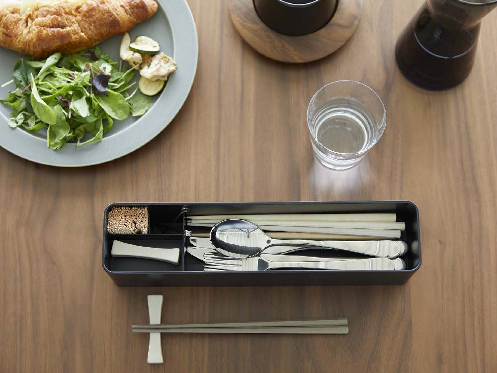 蓋付きロングカトラリーケース「tower/タワー」で、アクリル樹脂の蓋とABS樹脂の本体に複数の収納部があり、フォークやスプーン、箸などの食器類が整理されている様子