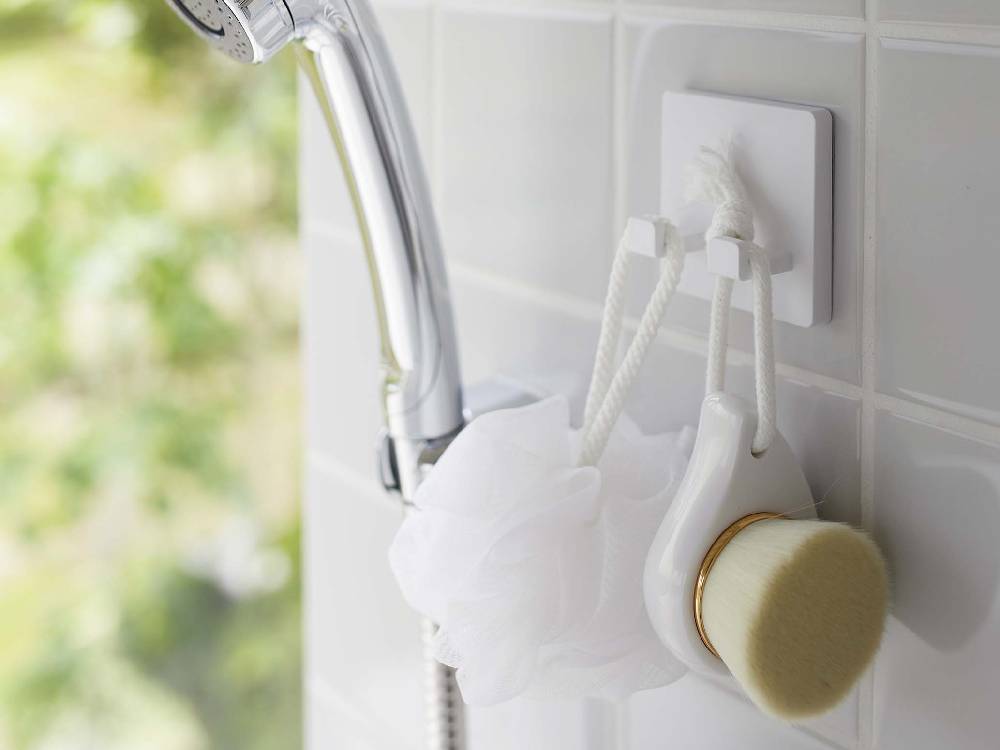 浴室の壁にフィルムで固定された【MIST/ミスト】フィルムフック シェーバーホルダーにシェーバーが掛けられている様子