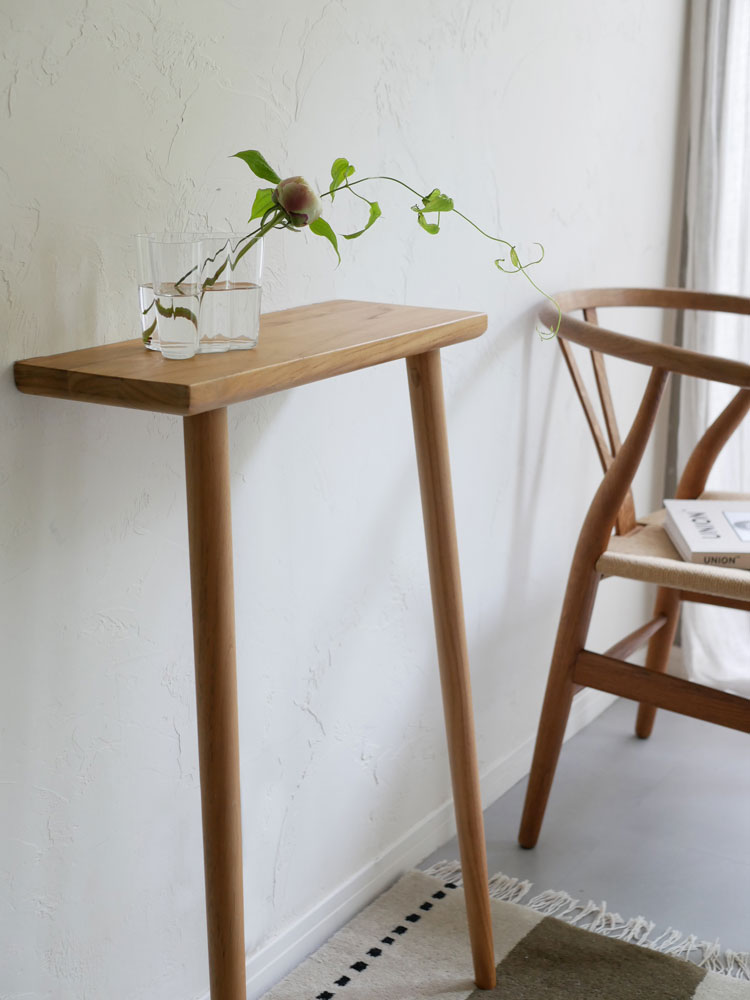 木製のエンドテーブルとスツールの上に鉢植えの観葉植物が配置されたインテリアの写真