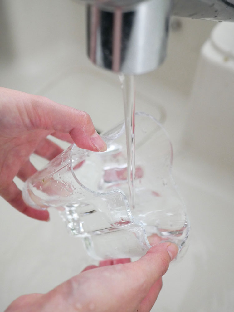 フィンランド製のイッタラ・アルヴァ・アアルトコレクション無鉛ガラスベースがシンクの上に置かれ、プラスチックボトルや飲料用ガラス瓶とともに配置されています。