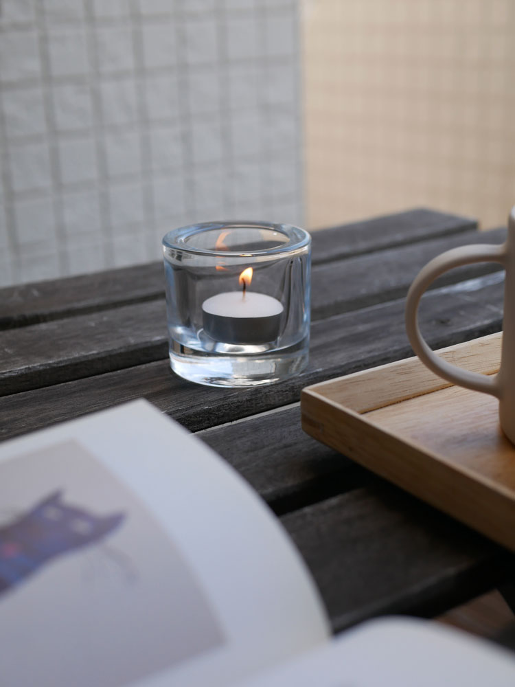 テーブル上に無鉛ガラス製のイッタラキビキャンドルホルダーが置かれ、キャンドルの炎が灯っている様子