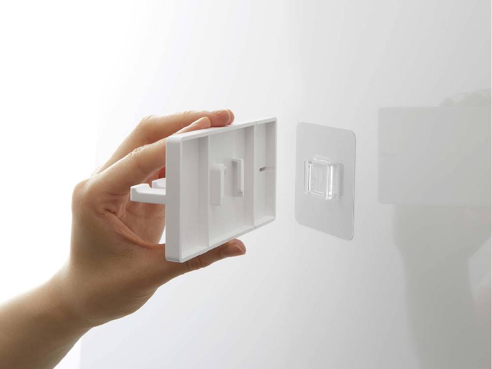 プラスチック製の5連フィルムフック歯ブラシホルダーが光沢のある壁面に取り付けられている様子