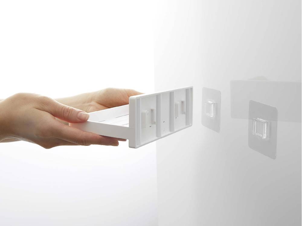 ABS樹脂製の【MISTフィルムフック トレー W18】が光沢のある壁面に取り付けられ、複数のAC電源プラグを整理している様子