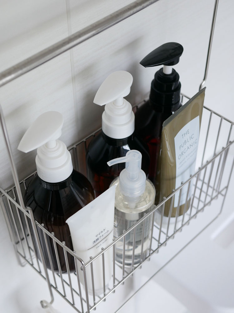 洗面台に取り付けられたHinata Lifeの18-8ステンレス製引っかけお風呂バスケットにソープディスペンサーやボトルが整理されているバスルーム