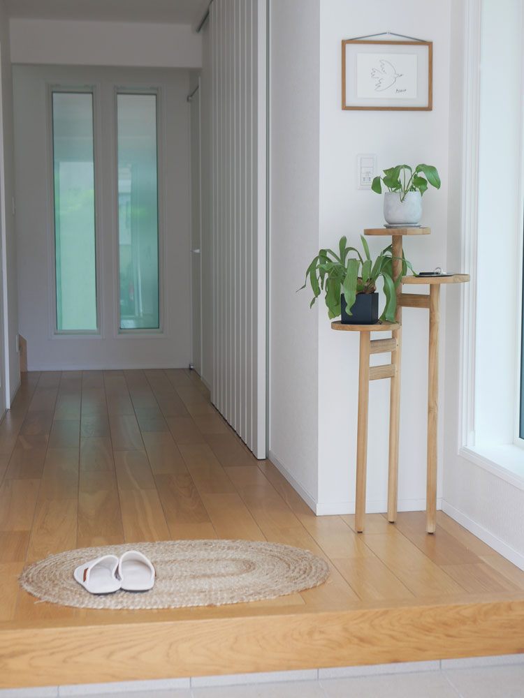 チーク無垢材のサンフラワーラタンステップトレイテーブルが木製フローリングの室内に配置された様子