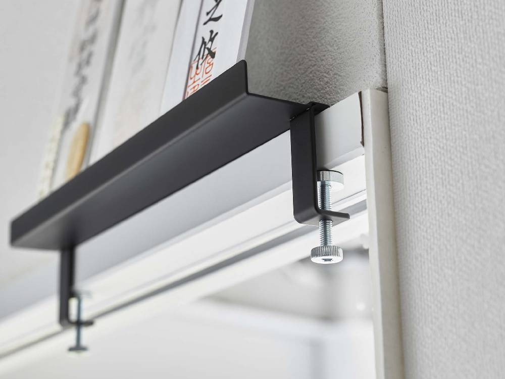 towerブランドのアルミニウム製鴨居上神札スタンドが木製の棚に取り付けられている様子。