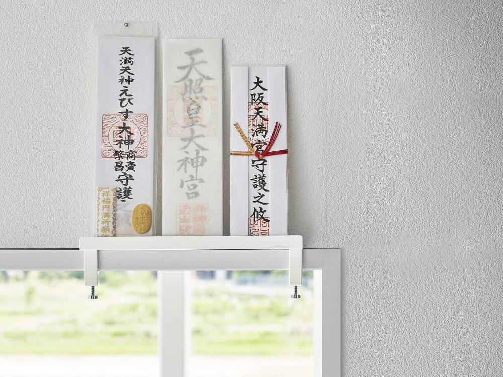 タワーブランドの鴨居上神札スタンドがオフィス用品や額縁と共にデスク上に配置された画像