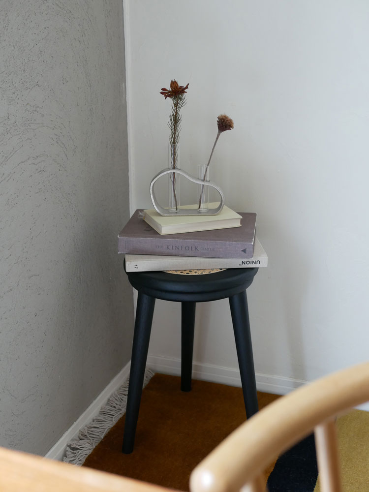 木製コーヒーテーブルの上にクレエの一輪が絵になるアルミガラスベースと観葉植物が配置されたナチュラルなリビングインテリア