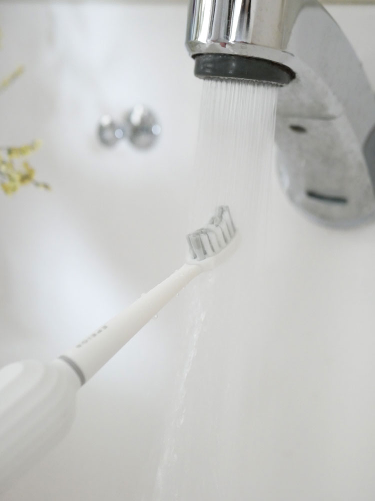 エペイオスのOkare音波電動歯ブラシと替えブラシヘッド、専用携帯ケースがバスルームの洗面台周辺に配置されている様子