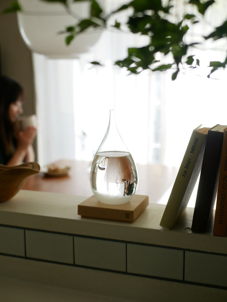 結晶の変化を楽しむ100percent Tempo Dropガラスボトルと木製ベースの静物写真