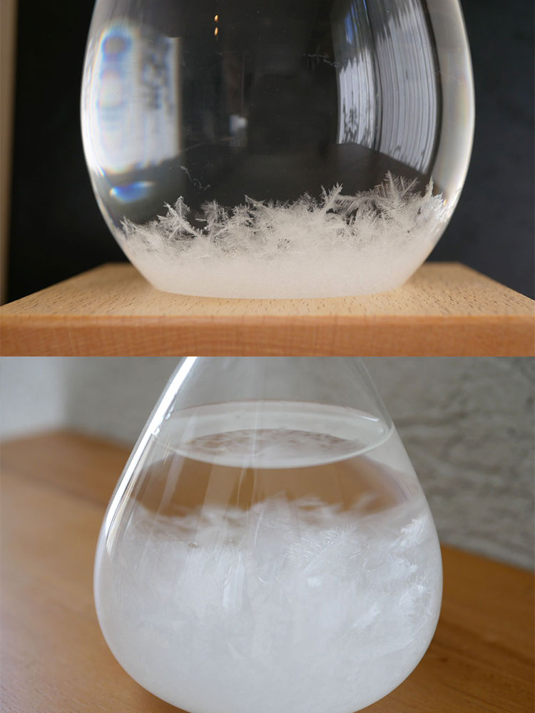 ガラス製のTempo Dropに透明な混合液が入っており、木製のベースの上に置かれた静物写真