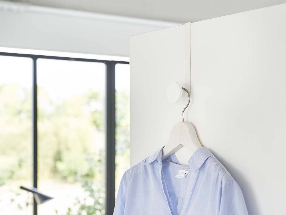 滑り止め付きスマートドアハンガーが標準的なドアに取り付けられ、シリコーンフックで服を掛けている様子。ステンレス製の本体が特徴的。
