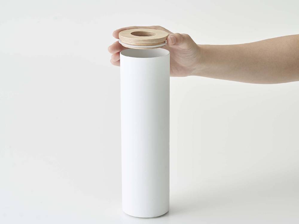 スチールと天然木で作られたボトル型ティッシュケース Sにティッシュペーパーが収納されている