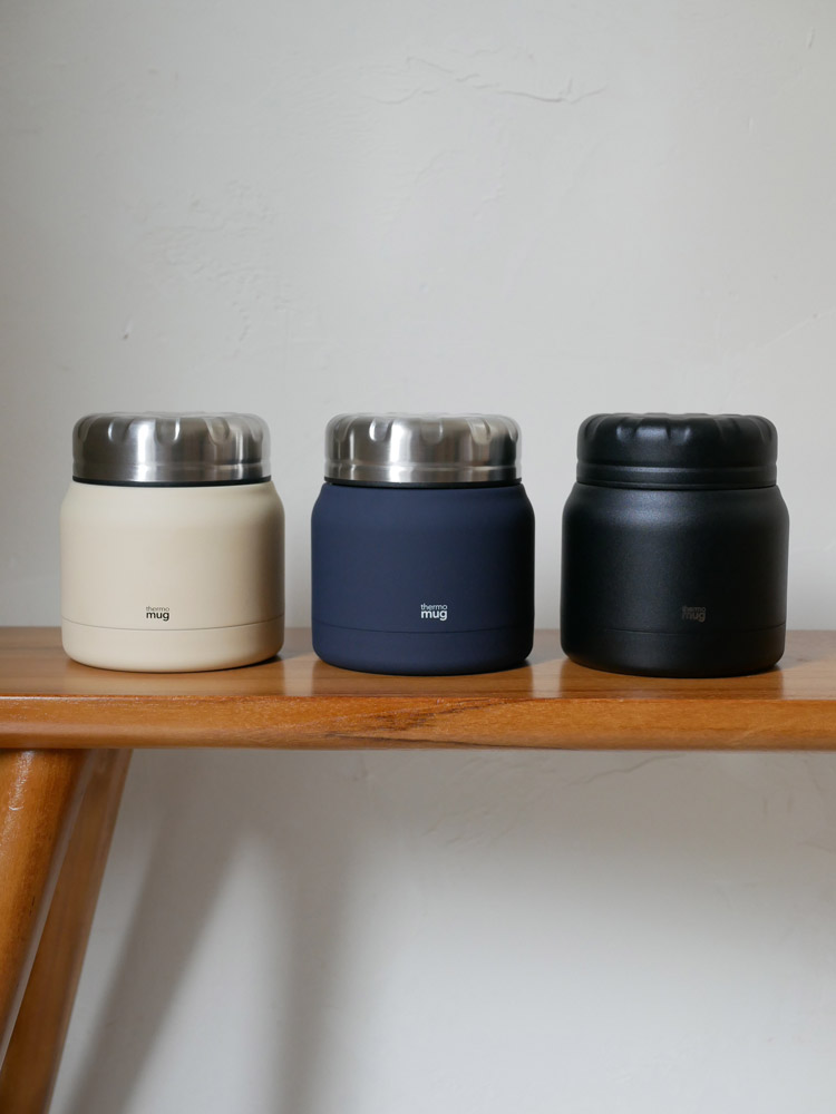 硬木のテーブル上に蓋付きのサーモマグとフードコンテナが並べられたセット