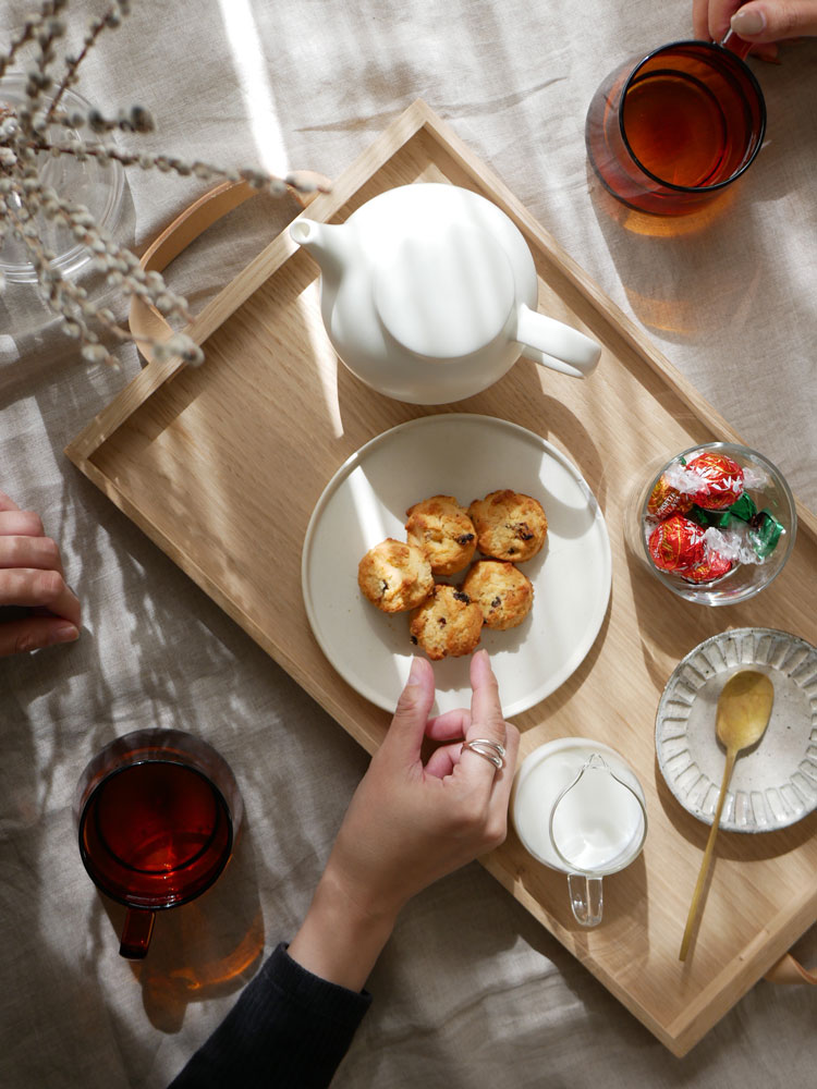 【FRITZ HANSEN/フリッツ・ハンセン】スカゲラック・ノールトレイにオークとレザー製の皿やカップが美しく配置されたテーブルウェア