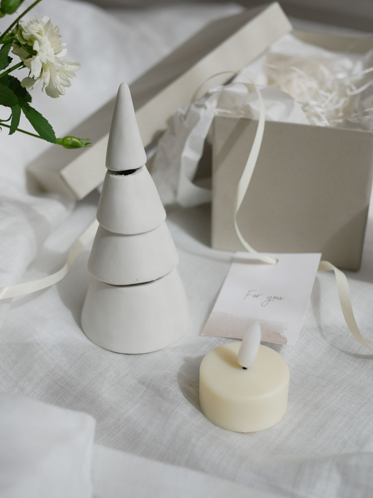 灯りが漏れる花坂陶石製の九谷焼クリスマスツリーに、紙製のオーナメントとコーンが飾られた装飾