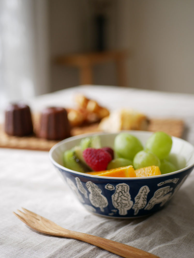 イッタラ×ミナ ペルホネン フォレストライフ2023限定カラーの磁器製テーブルウェアセット。ボウルやプレートにフルーツが美しく盛られた食卓の様子