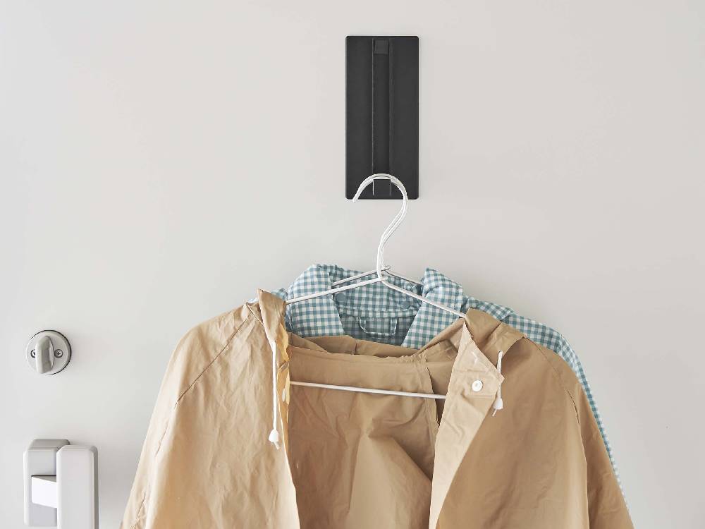 ホワイトのスチール製マグネット折りたたみハンガーが磁石で平らな壁面にしっかりと取り付けられている様子