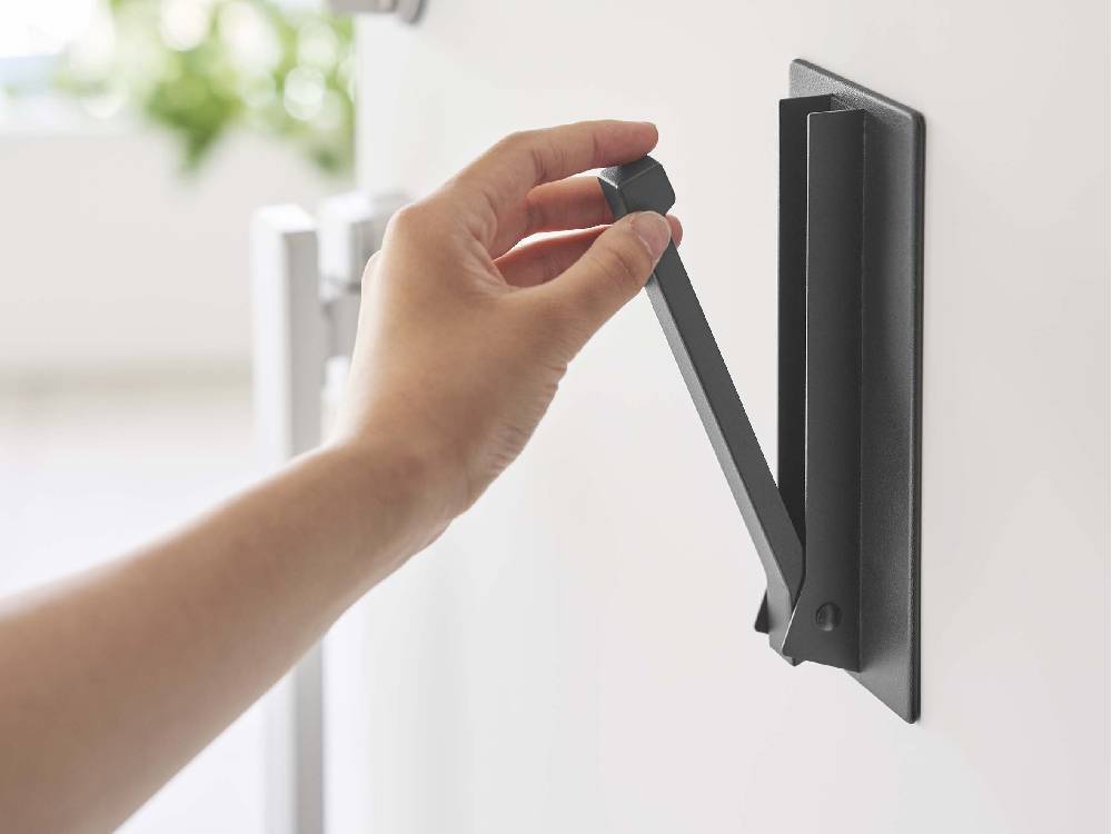 白色のマグネット折り畳みハンガーがドアハンドルに取り付けられている様子