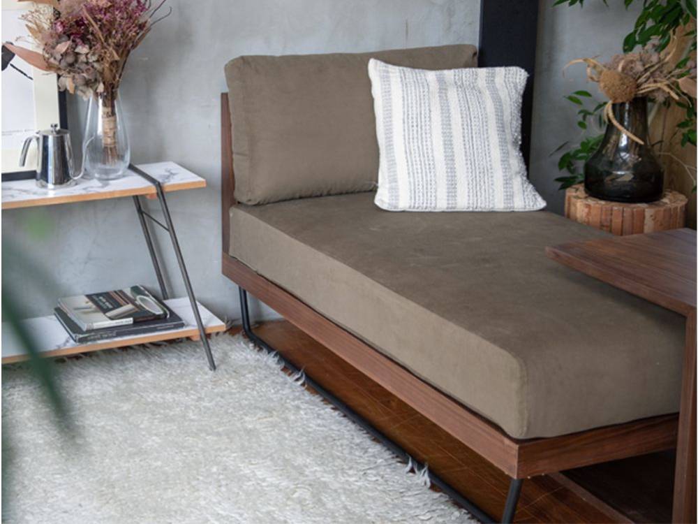 ブラウン色のウェルメカウチソファとクッションが配置されたスタイリッシュなリビングルーム