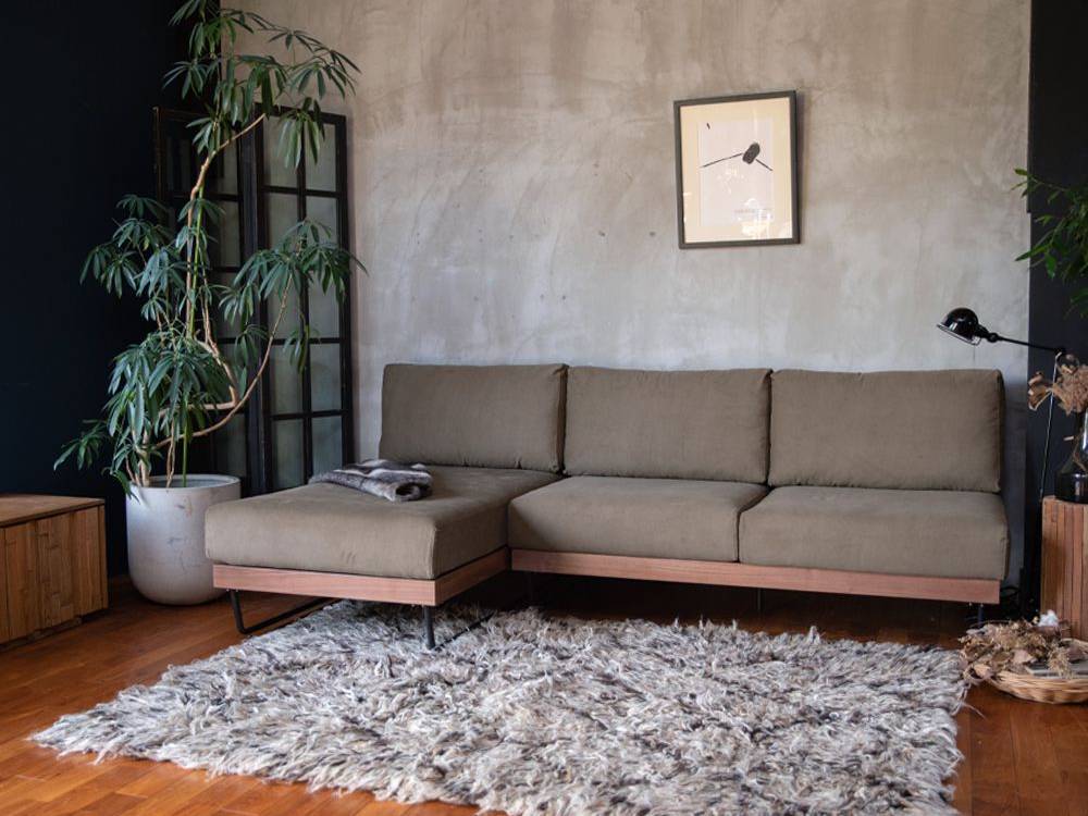 ブラウンのウォルナットフレームとアイアン脚を持つウェルメカウチソファがハードウッド床のリビングルームに配置されている