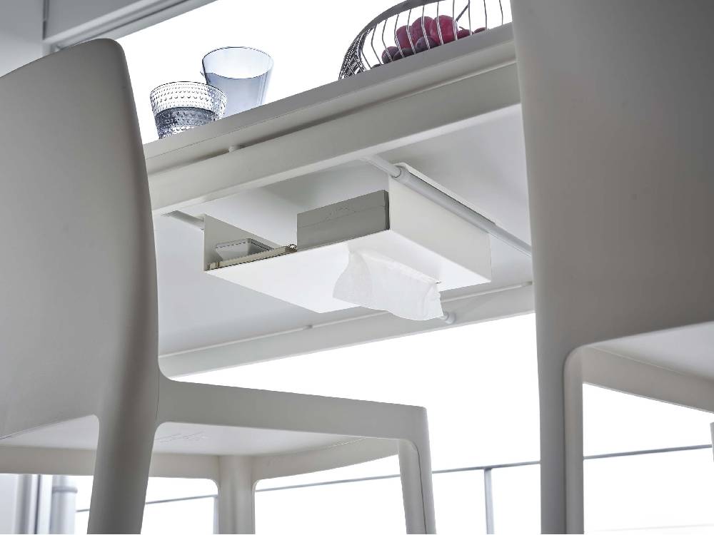 スチール製タワー型収納ラックがテーブル下のつっぱり棒に取り付けられており、小物を整理している様子