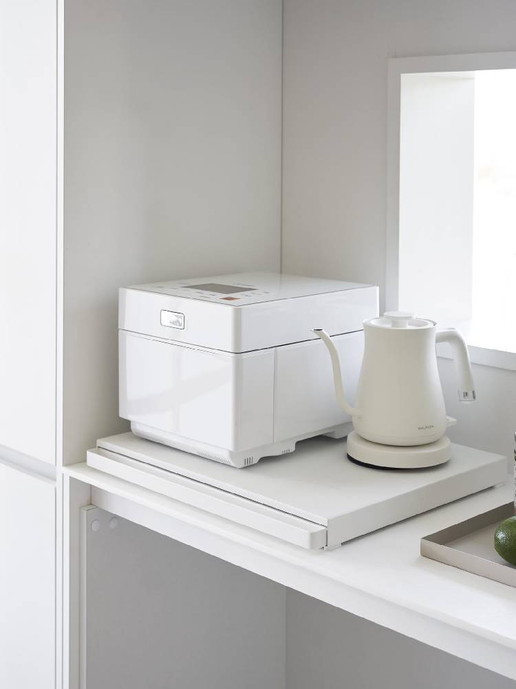 タワー型キッチン家電下にスライドテーブルが設置されたスチール製シェルフ。天板には小型家電が並び、収納スペースが確保されている様子