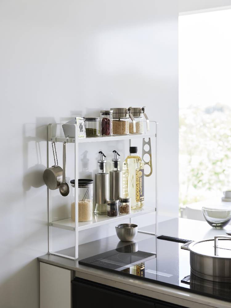 銀色のスチール製2段コンロ横ラックがキッチンカウンターに設置されており、上段と下段に棚が並んでいる様子。